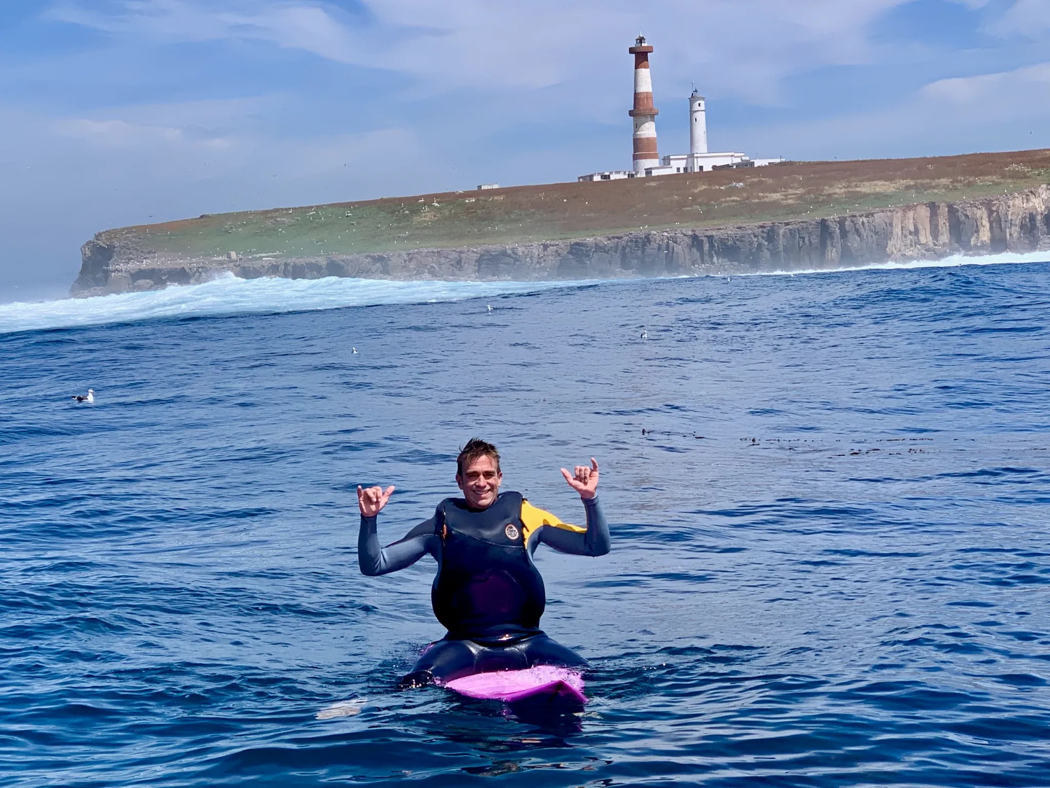 Andrew Howard sitting on the Pink Padillac in front of the lighthouse at Isla Todos Santos after surfing Killers
